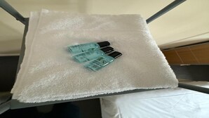 Una tovallola blanca sobre una prestatgeria de metall amb tres ampolles de loció corporal.