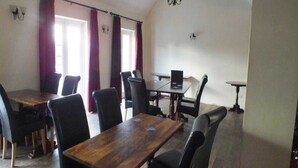 Una sala de conferències amb una taula de fusta, cadires negres i un ordinador portàtil sobre la taula.