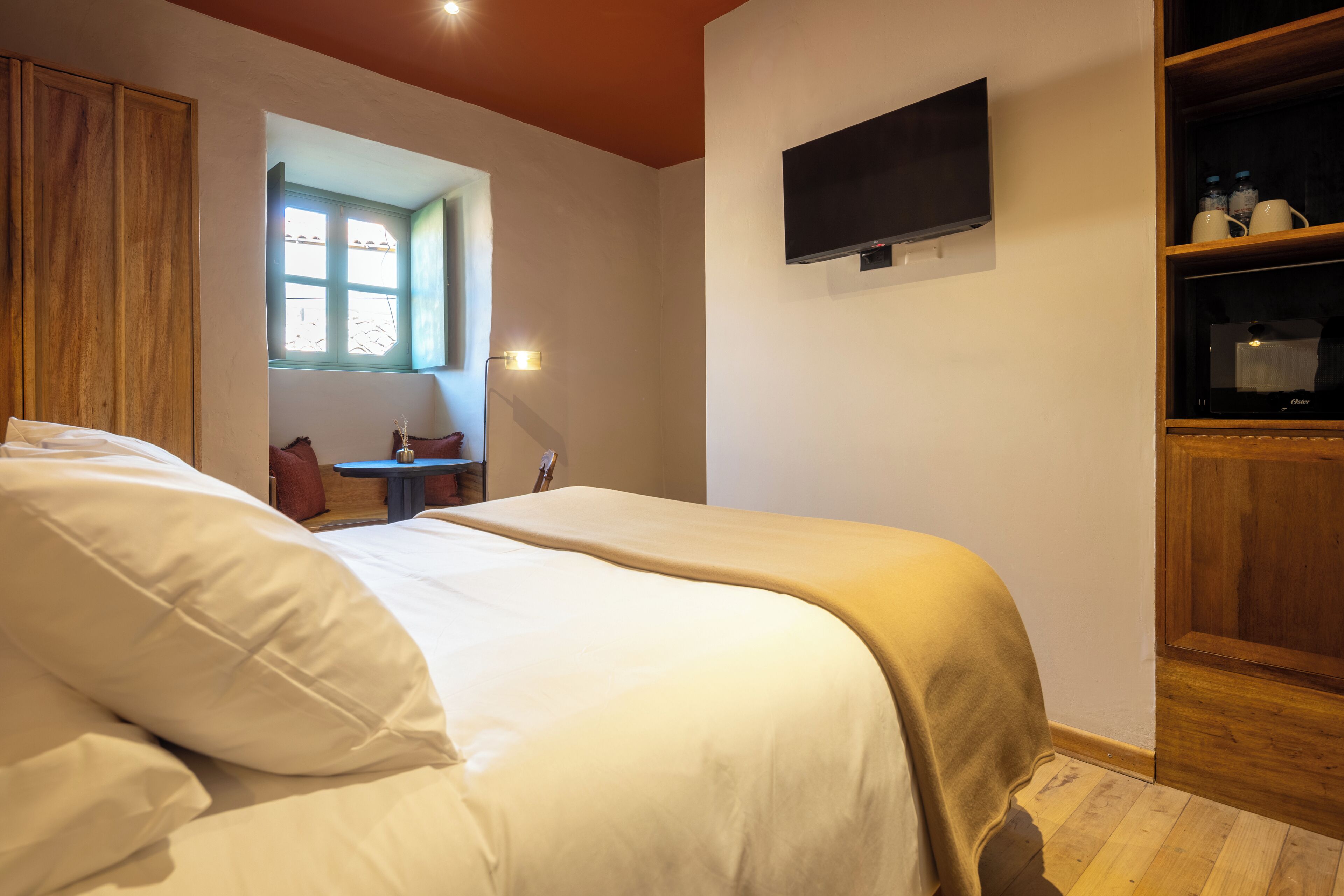 Ein Schlafzimmer mit einem Bett, einem an der Wand befestigten Fernseher und einem Holzschrank.