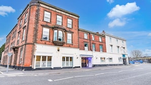 A corner building with a brick facade, a white storefront, and a sign for Aston Court Hotel.