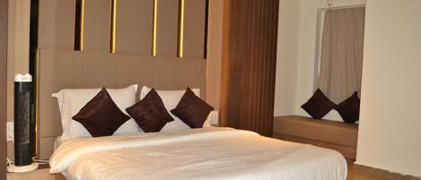 A modern hotel room with a large bed, a bedside table, a mirror, and a wall-mounted heater.