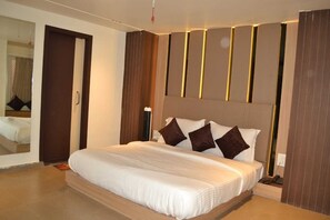 Une chambre à coucher moderne avec un grand lit, une tête de lit en bois et un miroir au mur.