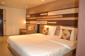 Une chambre d’hôtel moderne dotée d’un grand lit, d’un coin salon et d’un luminaire fixé au mur.