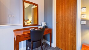 A wooden desk with a chair, a mirror, and a coffee maker. - Standard Family of 3 Room (Derby)