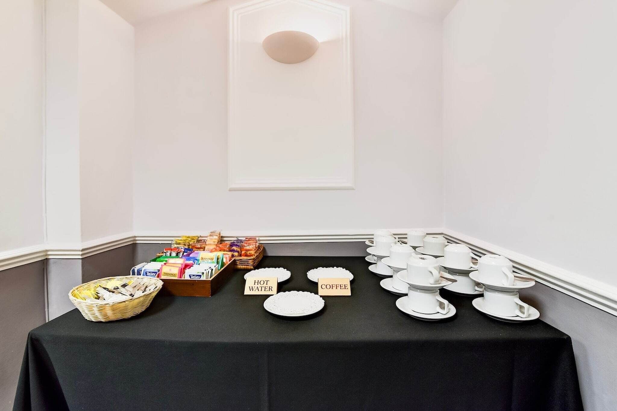 Ein Buffet mit beschrifteten Tellern für heißes Wasser und Kaffee sowie eine Auswahl an Snacks.