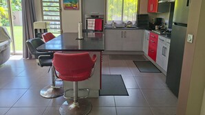 Eine moderne Küche mit einer zentralen Kochinsel, roten und weißen Schränken, einem Gasherd und einer Kaffeemaschine.