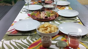 Ein gedeckter Tisch mit tropischem Muster, Tellern, Gläsern und verschiedenen Speisen.
