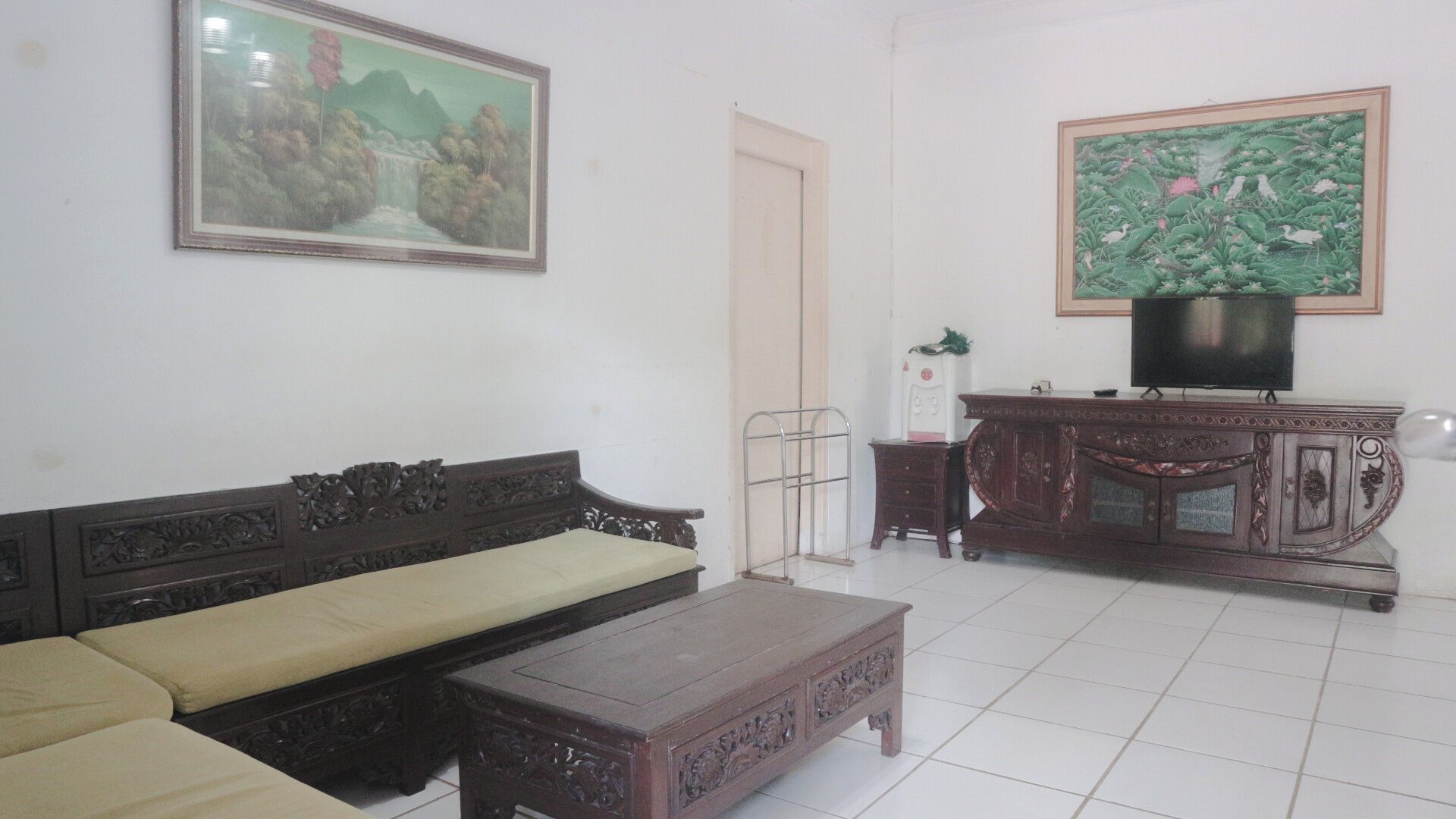 Una sala de estar con un sofá, una mesa de centro, un televisor y dos cuadros en la pared.