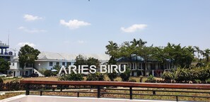A building with the sign 'ARIES BIRU' and a clear sky. - Aries Biru Hotel & Villa (Cisarua)