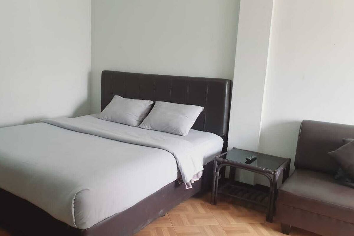 A bedroom with a bed, a nightstand, and a sofa.