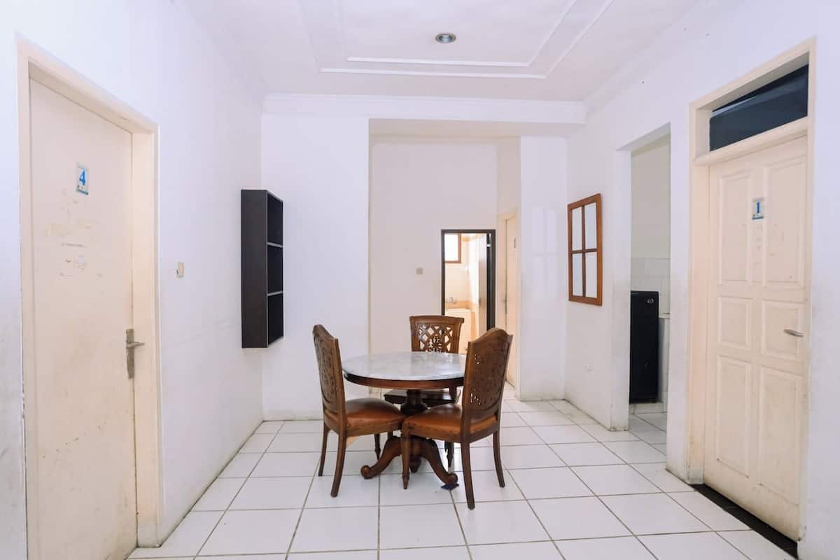 A dining area with a round table and four chairs, white tiled floor, and white walls.