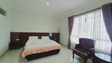 Una habitación de hotel con una cama grande, un cabecero de madera, una silla y una mesita.