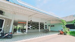 A covered outdoor area with a checkered floor, a motorcycle, and a sign for 'OBBY ARIES UTAMA'. - Aries Biru Hotel & Villa (Cisarua)