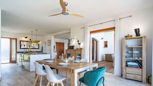 A modern kitchen with a wooden island, white chairs, and a teal chair. - Villa Castille – Pool and Sea View in Lumio, Balagne (LUMIO)