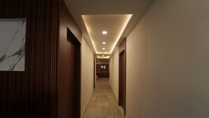 A hallway with wooden paneling, recessed lighting, and a marble wall. - Icon Residency Inn (Prayagraj)