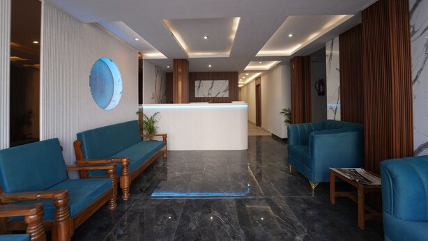 A modern lobby with a reception desk, blue sofas, wooden chairs, and a marble floor. - Icon Residency Inn (Prayagraj)
