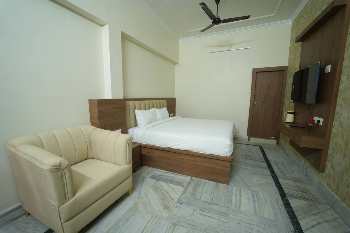 Un dormitorio con cama, sofá, ventilador de techo, televisor y armario.
