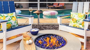 A poolside seating area with chairs and a fire pit. - Private Pool, Firepit, Game Room | Mins to Beaches | Casa Solara by AvantStay (Naples)