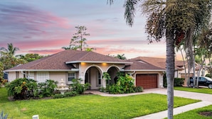 A residential house with a well-maintained lawn, a driveway, and a garage. - Private Pool, Firepit, Game Room | Mins to Beaches | Casa Solara by AvantStay (Naples)