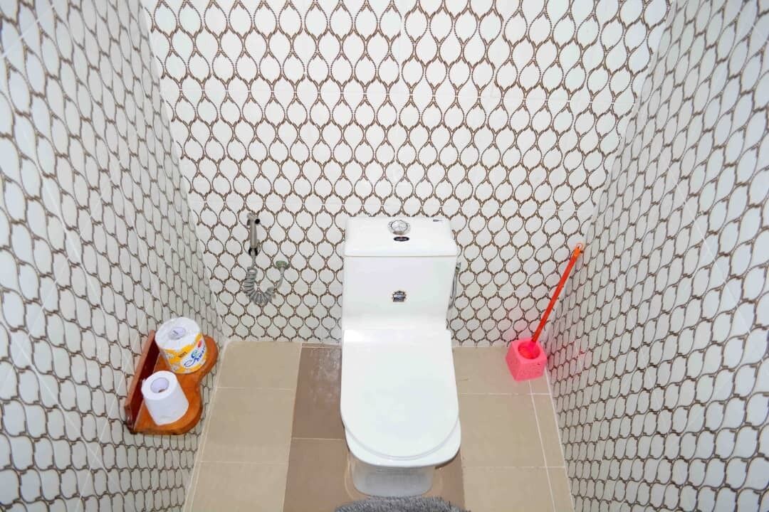 Un baño con inodoro, escobilla y portaescobillas.