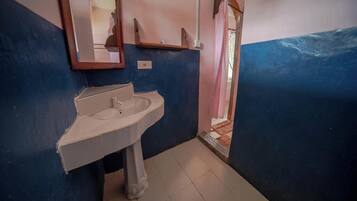 Un baño con lavamanos, espejo y puerta que da a otra habitación.