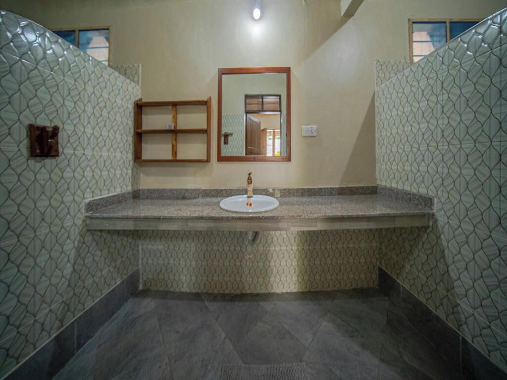 A bathroom with a large sink, a mirror, and patterned walls.
