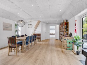 Une pièce spacieuse comprenant une table à manger en bois, des chaises, une bibliothèque et un drapeau.