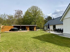 Un espace extérieur moderne doté d’une terrasse en bois, d’un jacuzzi et d’un patio avec mobilier d’extérieur.