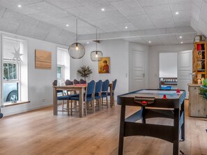 A spacious room with a pool table, dining area, and a door leading to another room.