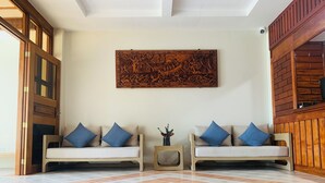 A room with two sofas, a patterned floor, and a wooden wall panel. - Belau Almond Hotel (Malakal Island)