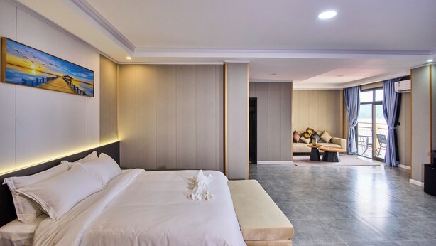 A modern hotel room with a large bed, a painting on the wall, and a view of the balcony. - Belau Almond Hotel (Malakal Island)