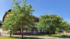 Un bâtiment doté d’un toit plat, avec un grand arbre en premier plan.