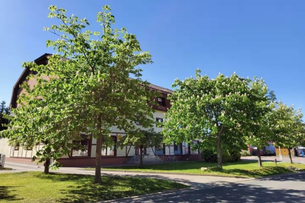A building with a flat roof and a large tree in the foreground.