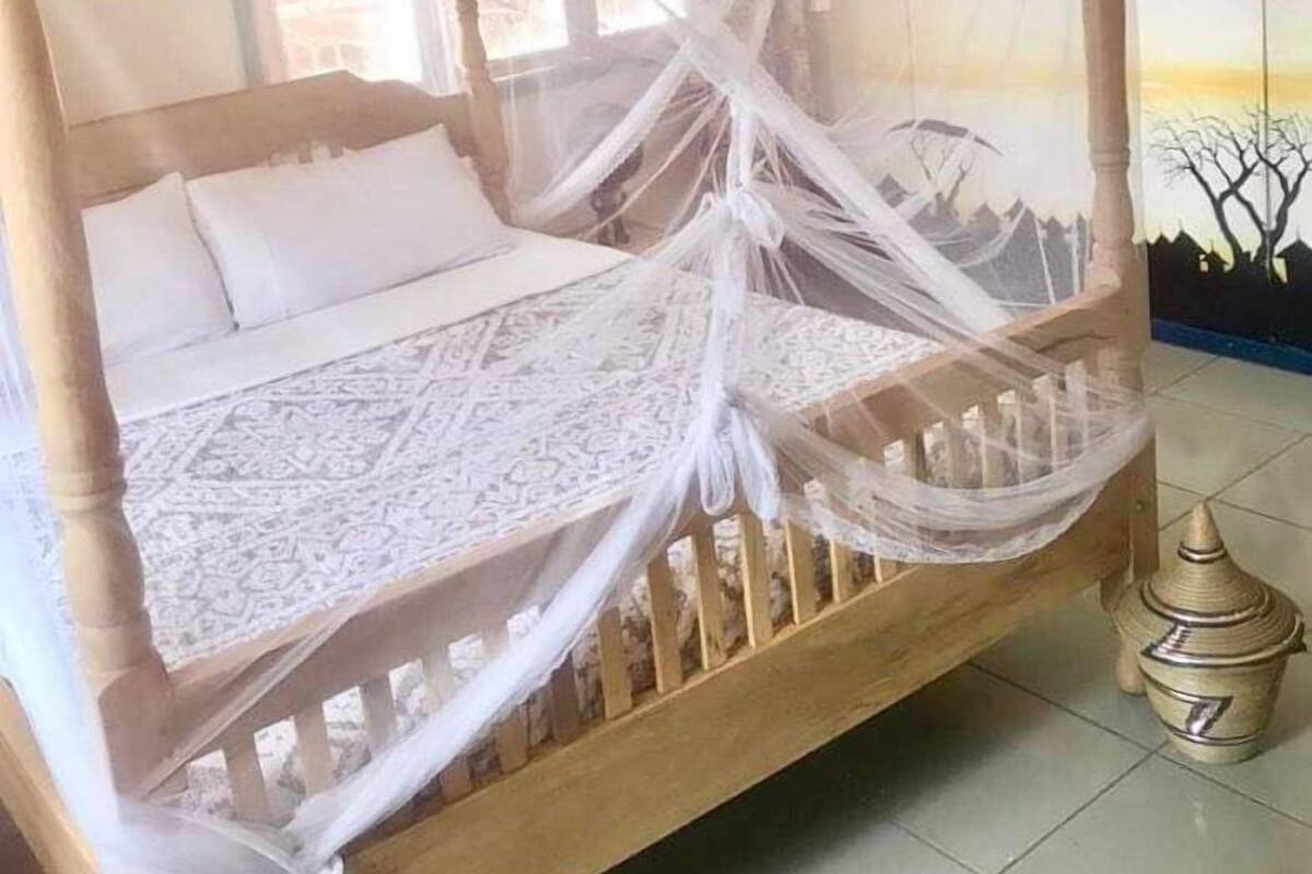 A bed with a mosquito net, a patterned bedspread, and a wooden frame.