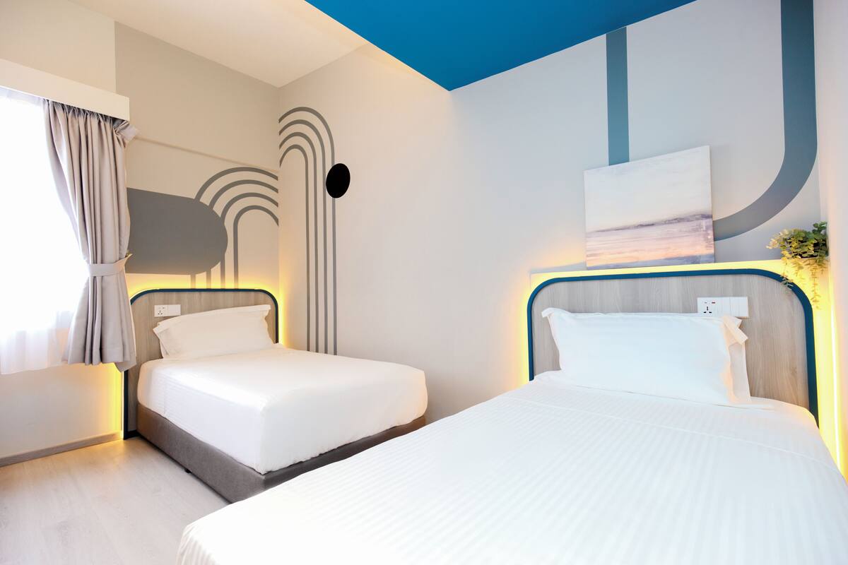 Een moderne hotelkamer met twee bedden, een groot raam met gordijnen en een wandkunstwerk.