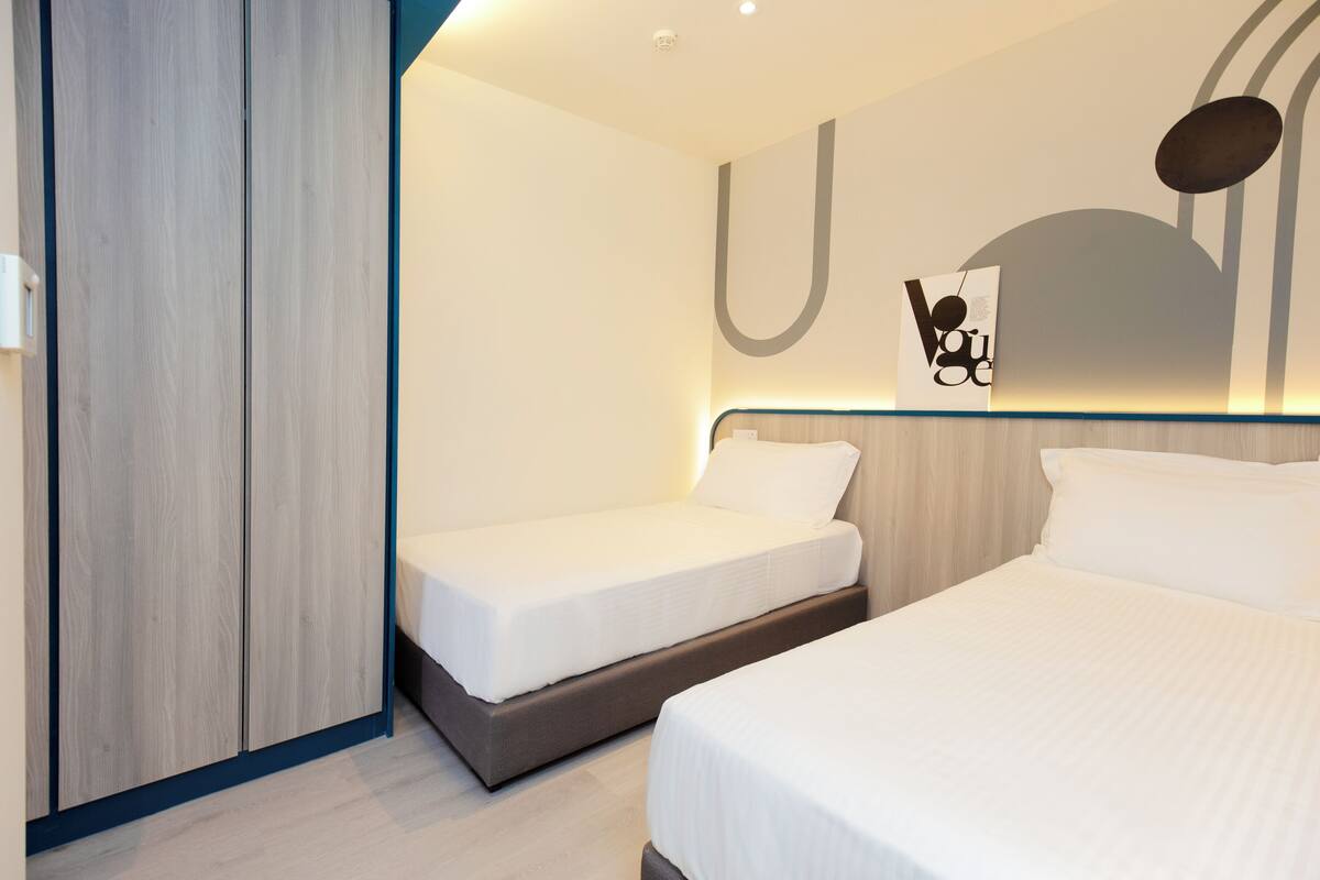 Een hotelkamer met twee bedden, een houten garderobe en een kunstwerk aan de muur.