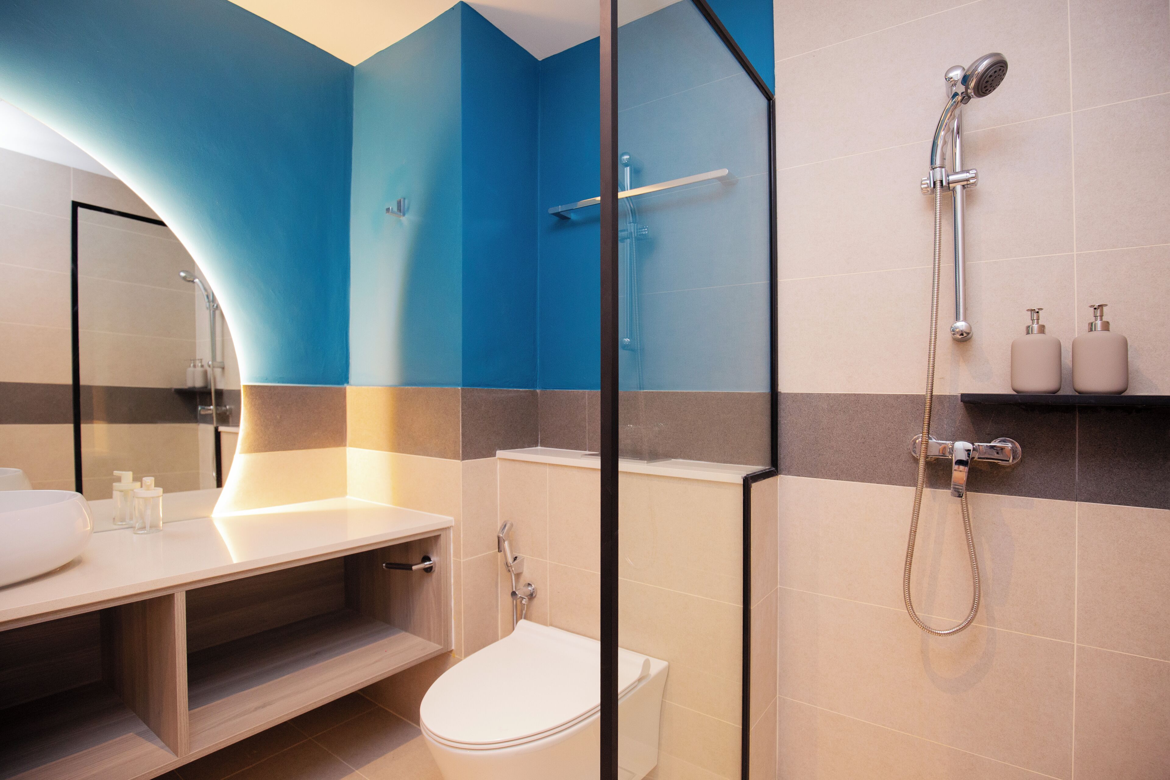 Un baño moderno con cabina de ducha de vidrio, inodoro blanco y tocador con espejo.