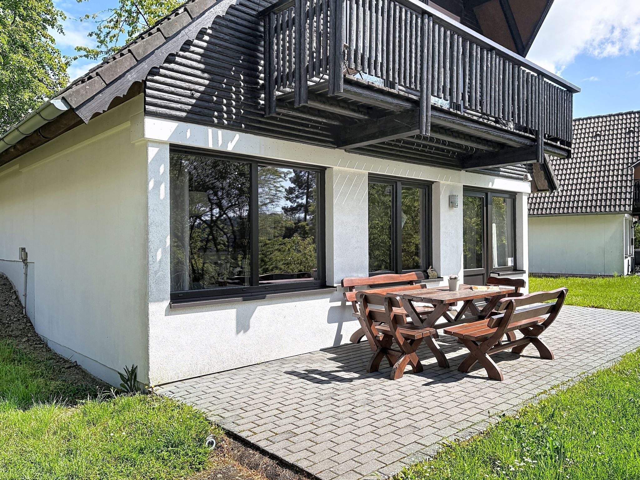 A house with a patio, large windows, and a wooden deck.