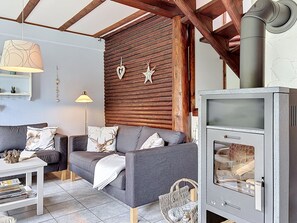 Un salon chaleureux avec un canapé, une table, une cheminée et des lambris en bois.