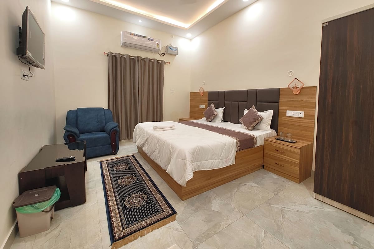 Een slaapkamer met een bed, bureau, stoel, airconditioning en een kledingkast.