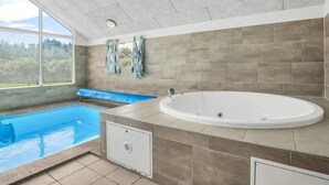 Un baño moderno con una bañera grande, zona de ducha y ventana con vistas al exterior.