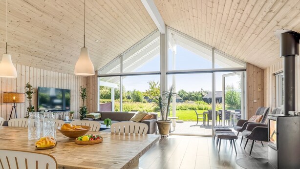 Un salón amplio con una gran mesa de madera, asientos cómodos, chimenea y vistas al exterior.