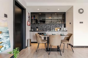Uma cozinha moderna com painel de backsplash em preto e branco, duas cadeiras e uma mesa de jantar.