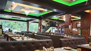 A restaurant with booths and tables, some with gold utensils and placemats. - Hotel Shani - Punjabi Rasoi (Palampur)