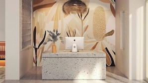 A reception area with a speckled countertop, a computer monitor, and a decorative wall with abstract floral patterns. - The Signature Retreat & Pool Phu Quoc (Phu Quoc)
