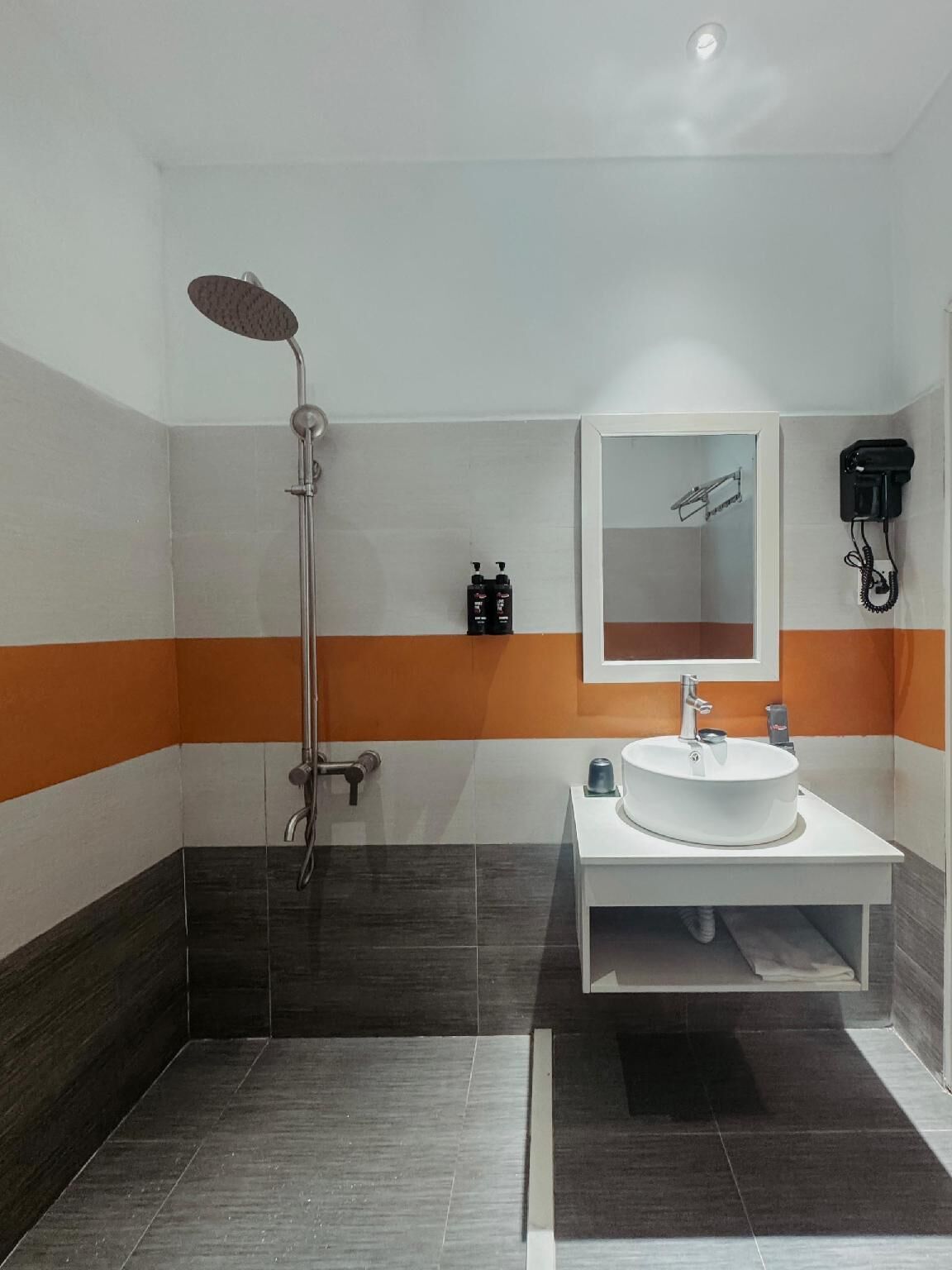 Un baño moderno con ducha, lavamanos y espejo.