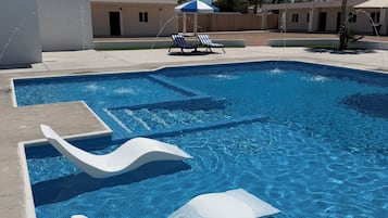 Una piscina con toboganes, sillas de descanso y una palmera.