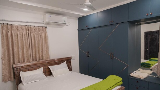 A bedroom with a bed, a wardrobe, a mirror, and an air conditioning unit. - Karthikeya Guest Inn  (Hyderabad)