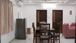 A dining area with a table and chairs, a refrigerator, and a ceiling fan. - Karthikeya Guest Inn  (Hyderabad)