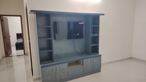 A room with a built-in entertainment unit, a door leading to another room, and a tiled floor. - Karthikeya Guest Inn  (Hyderabad)
